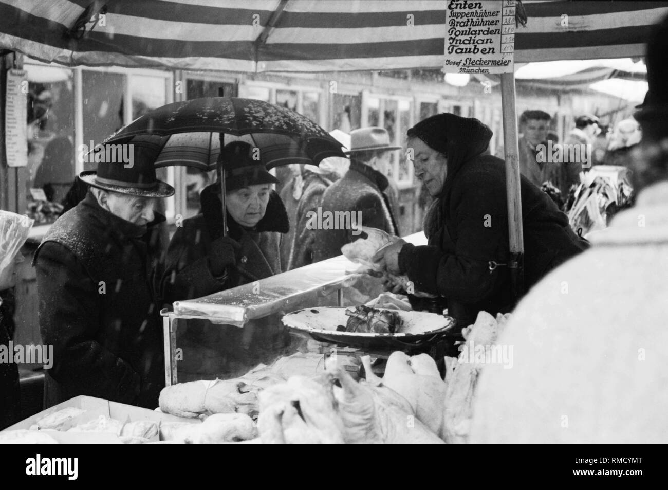 Una donna di mercato vende carni di pollame a Josef Stechermeier stand. Foto Stock