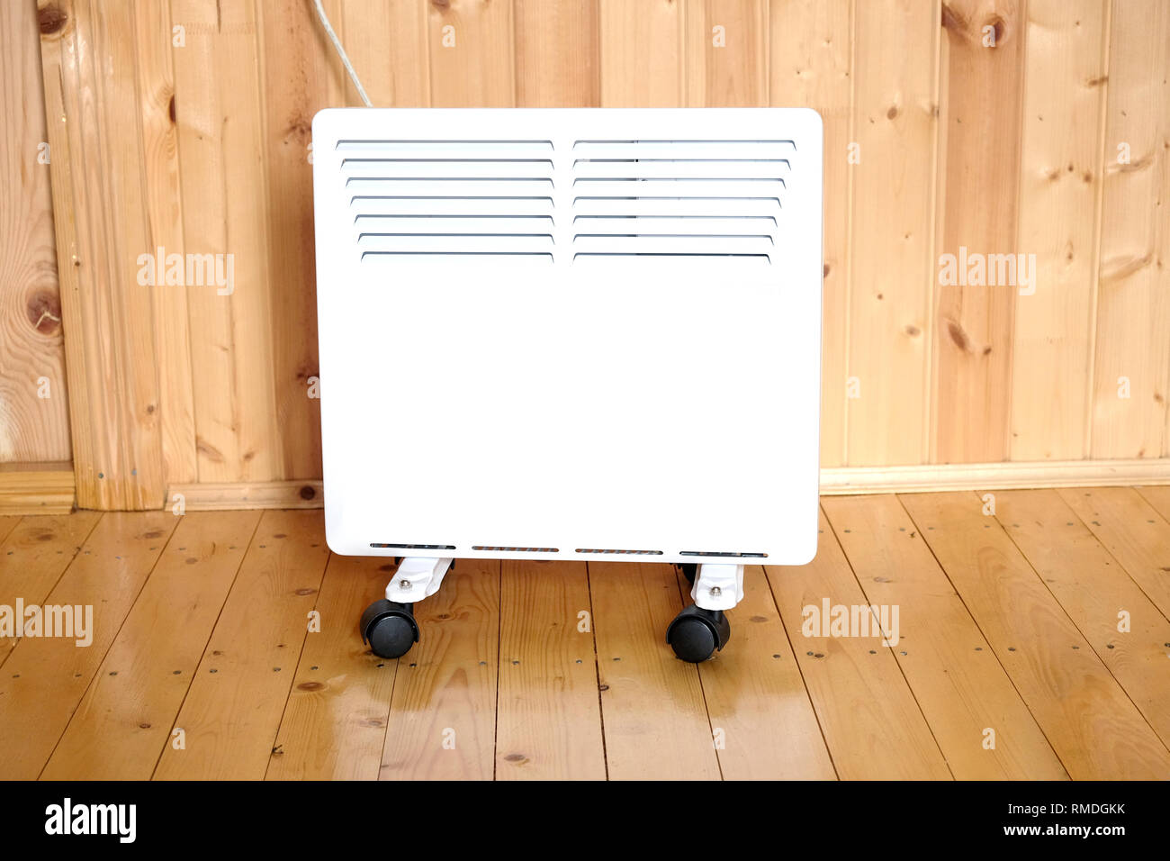 Lavoro elettrico bianco termoconvettore collegato alla linea di alimentazione in una casa di legno camera vista anteriore closeup Foto Stock