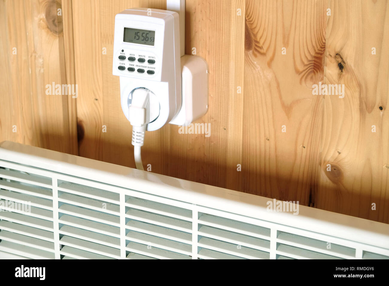 Lavoro elettrico bianco termoconvettore collegato al timer presa di alimentazione azionata in casa intelligente sistema contro la parete di legno all'interno camera vista laterale vista dettagliata Foto Stock