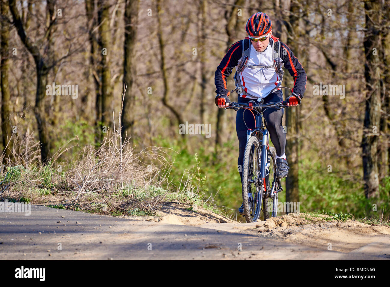 Sport ciclista viaggia lungo un sentiero nella foresta su una molla giornata di sole. Foto Stock