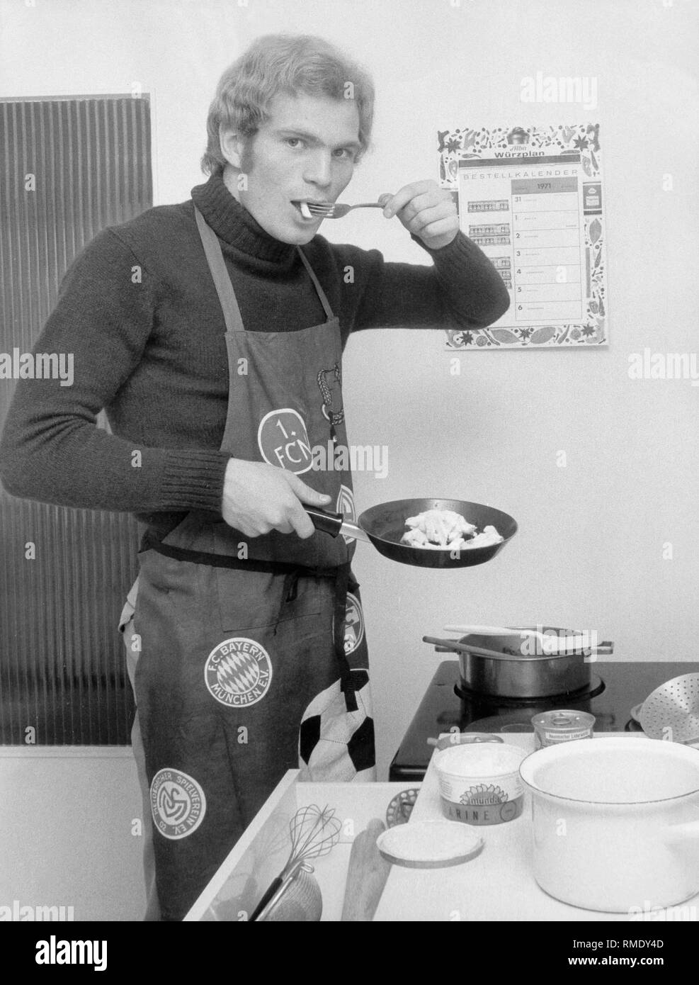 Calciatore e corso di laurea Uli Hoeness con il calciatore grembiule quando la cottura nella cucina del suo appartamento di Monaco di Baviera - Trudering. Foto Stock