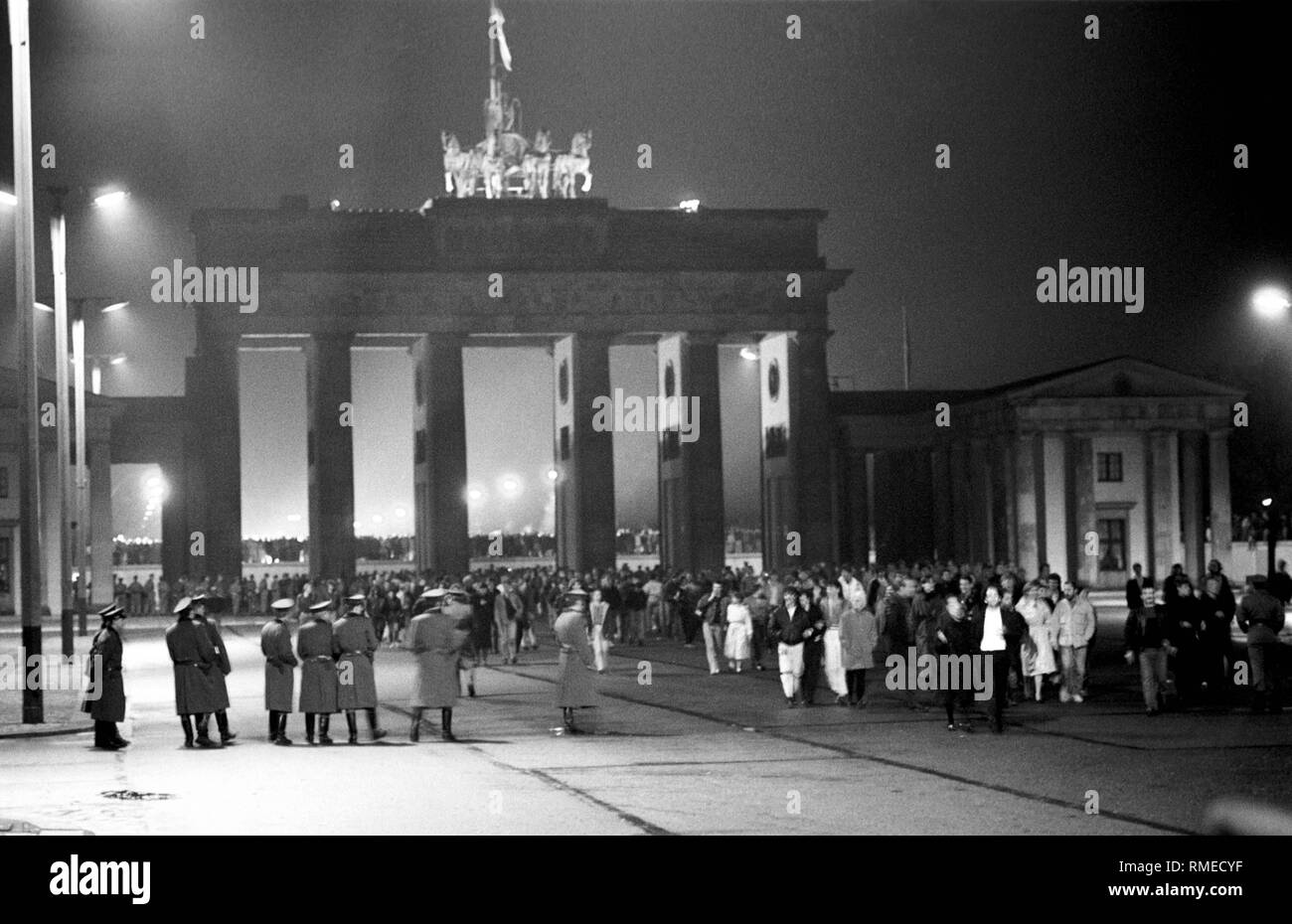 Vista da Berlino est alla Porta di Brandeburgo nella notte del 9 al 10 novembre, dopo la "caduta del Muro". I cittadini di Berlino Ovest e Berlino Est stand sotto la porta e sulla parete (dietro), GDR truppe di frontiera sono di fronte e al di sotto del gate. Foto Stock
