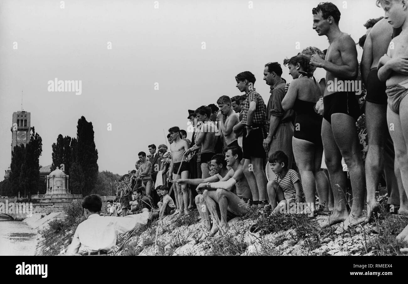 Gli spettatori che indossa la balneazione scivola a guardare le operazioni di soccorso all'Isar a Monaco di Baviera. Foto Stock