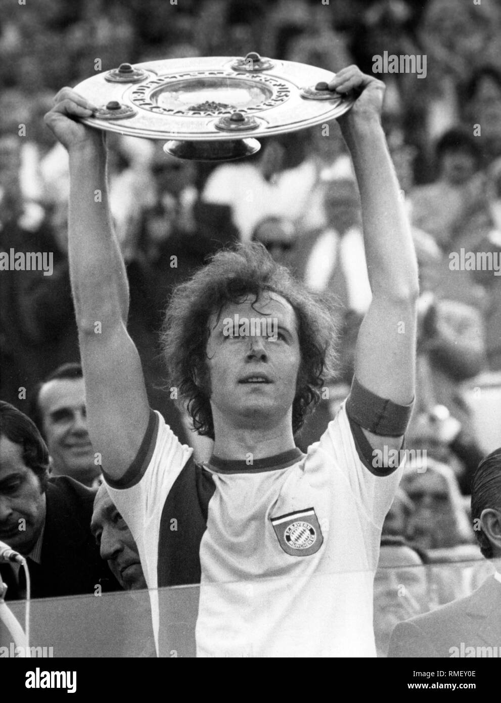 Franz Beckenbauer trattiene il Meisterschale in aria come un giocatore a FC Bayern Monaco di Baviera, dopo FC Bayern Monaco di Baviera è diventato campione tedesco di calcio. Foto Stock