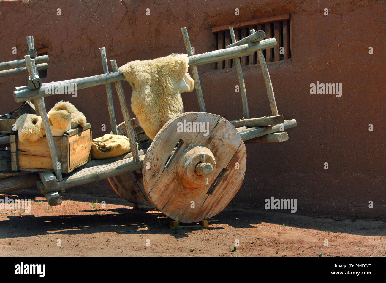 Carrello messicano ha enormi ruote di legno e mozzi in legno. Il carrello si siede di fronte a una casa adobe. Foto Stock