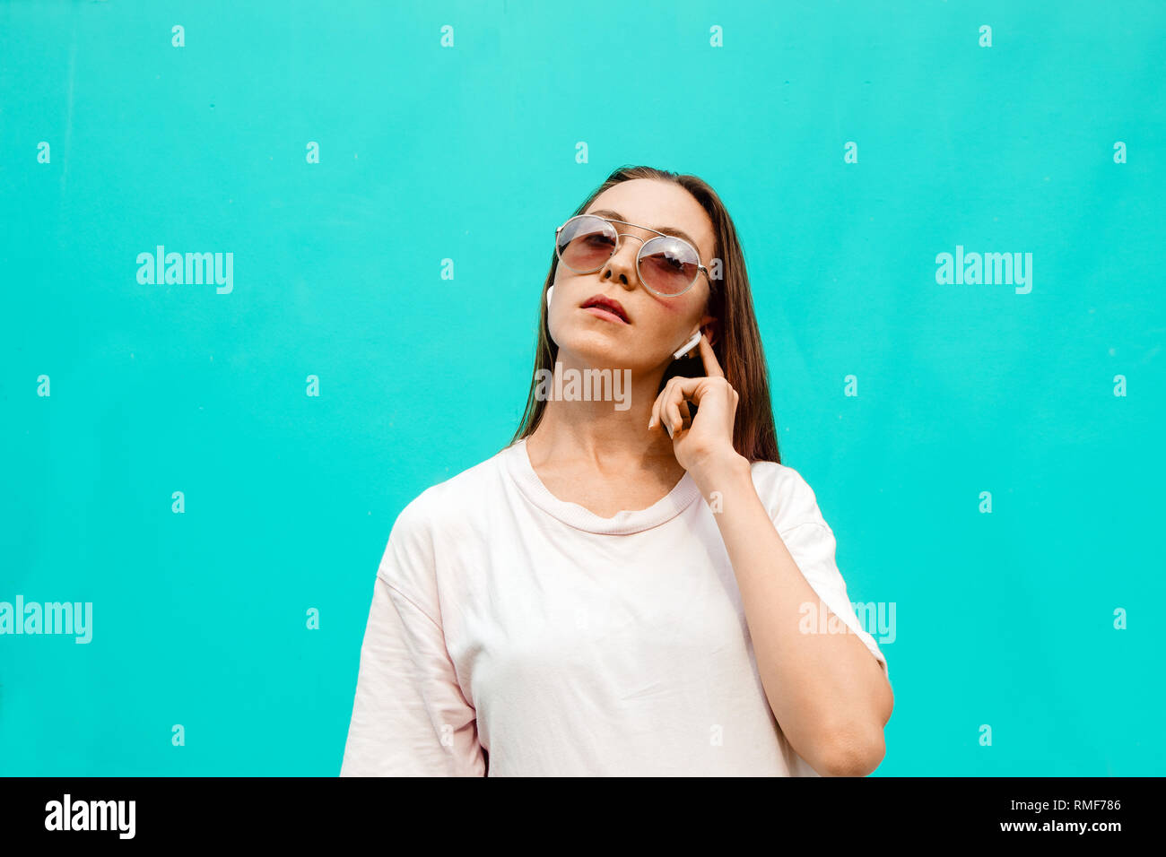 Giovane donna in occhiali da sole con auricolari Foto Stock