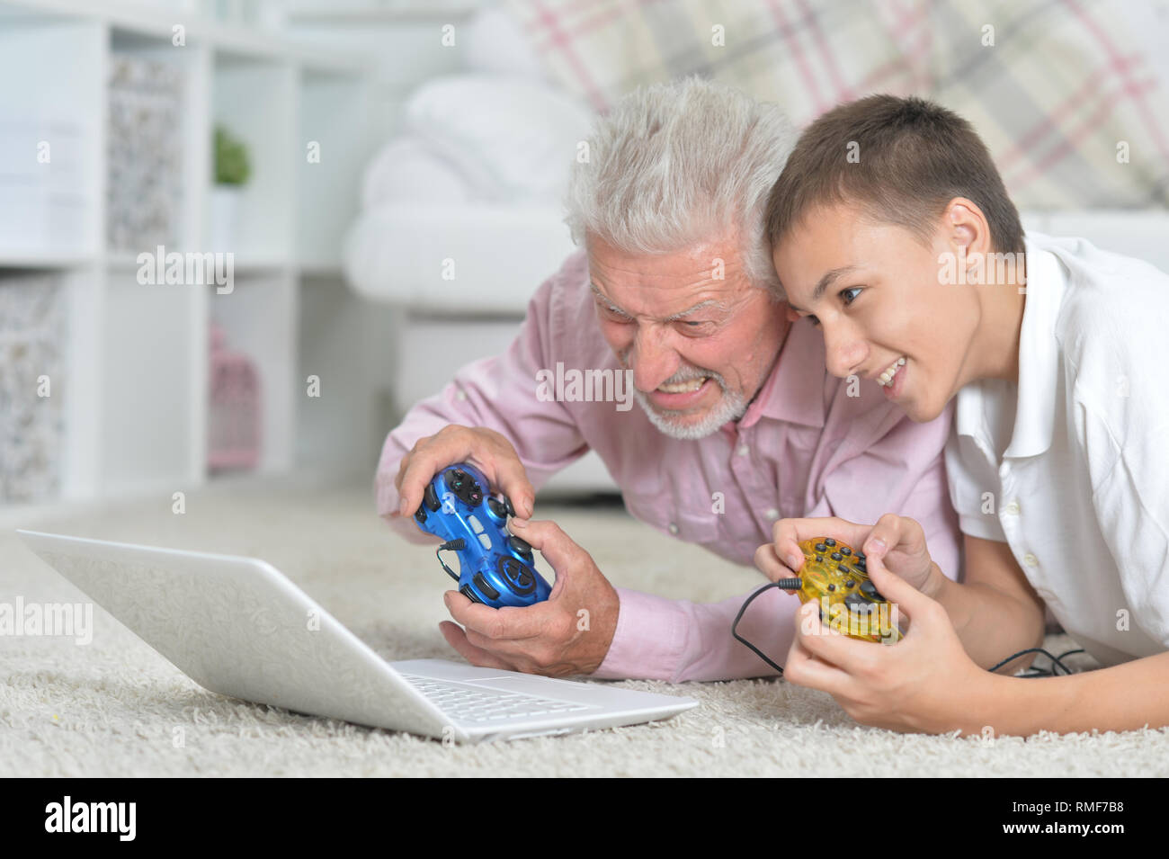 Ritratto di nonno e nipote sdraiato sul pavimento e i giochi per computer sul computer portatile Foto Stock