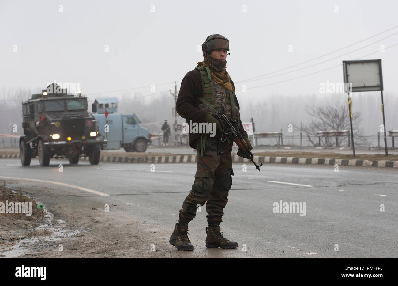 Srinagar, Indiano-controllato del Kashmir. 15 Feb, 2019. Un esercito indiano trooper sta di guardia come la sicurezza e il team legale di ispezionare il relitto di veicoli presso il sito di un attacco suicida su una autostrada nazionale Lethpora vicino villaggio nel distretto di Pulwama, circa 27 km a sud di Srinagar city, la capitale estiva di Indiano-Kashmir controllata, Feb 15, 2019. Il numero di vittime di un attacco suicida di targeting di paramilitari troopers appartenenti alla riserva centrale forza di polizia (CRPF) in irrequieta indiano-Kashmir controllato il giovedì è salito a 40, hanno detto i funzionari. Credito: Javed Dar/Xinhua/Alamy Live News Foto Stock