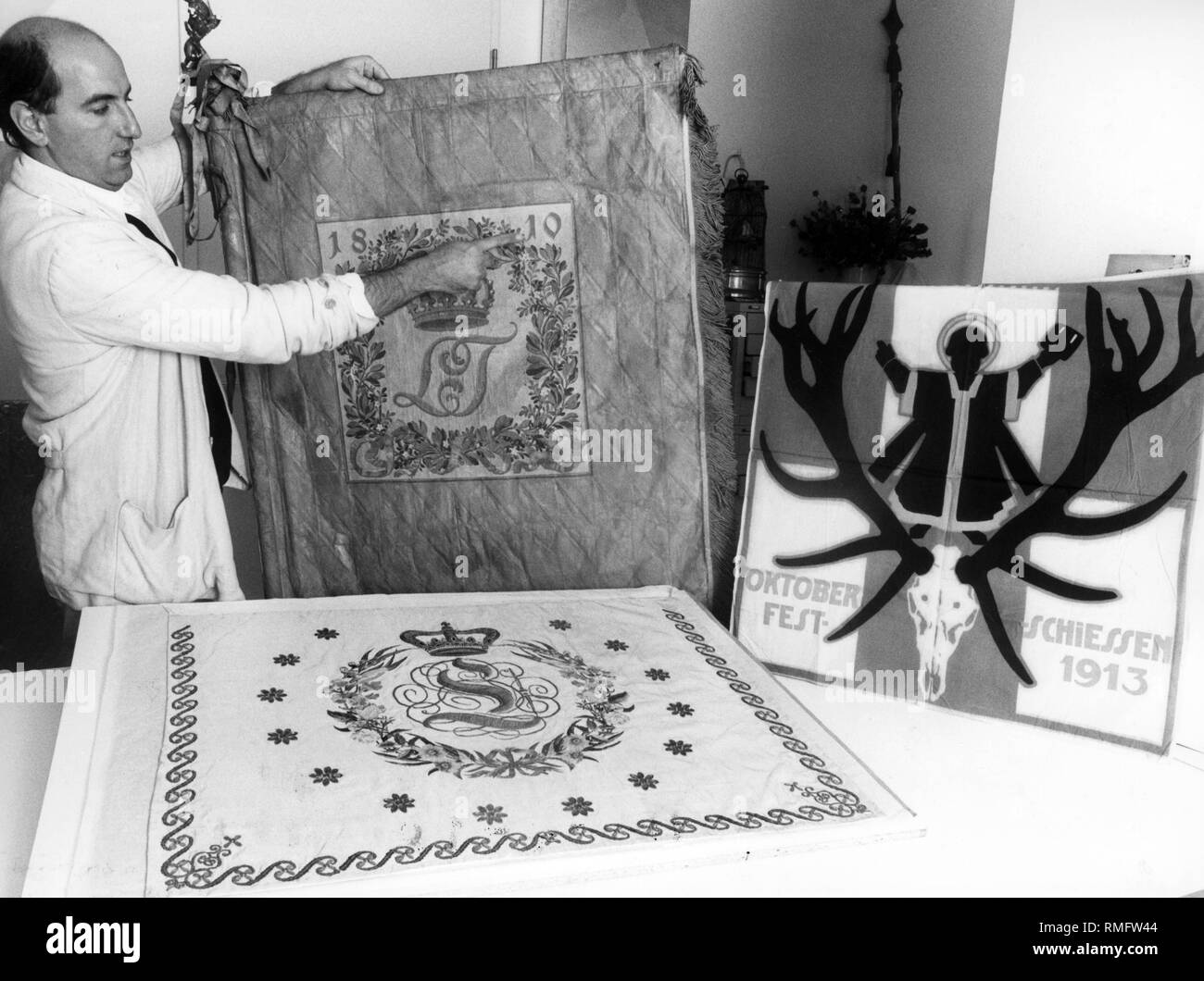 Dal 25 Luglio al 3 novembre il Stadtmuseum di Monaco di Baviera ha ospitato la mostra anniversario della 175Oktoberfest. Florian Dering, direttore scientifico dell'Oktoberfest mostra con un LT 1810 bandiera (LT per Ludwig e Teresa), che risale al 1910, quando il centesimo anniversario della mostra è stato celebrato. Il flag accanto ad esso è dal Oktoberfestschiessen nell'anno 1930, ed è stato un premio per il vincitore di una corsa di cavalli. Foto Stock