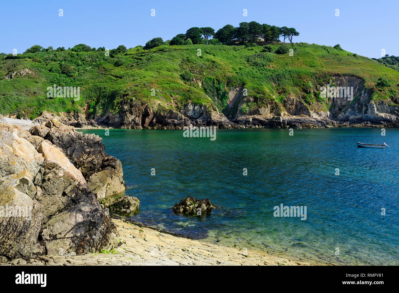 Acqua blu e scogliere in Saints Bay Harbor, Guernsey. Foto Stock