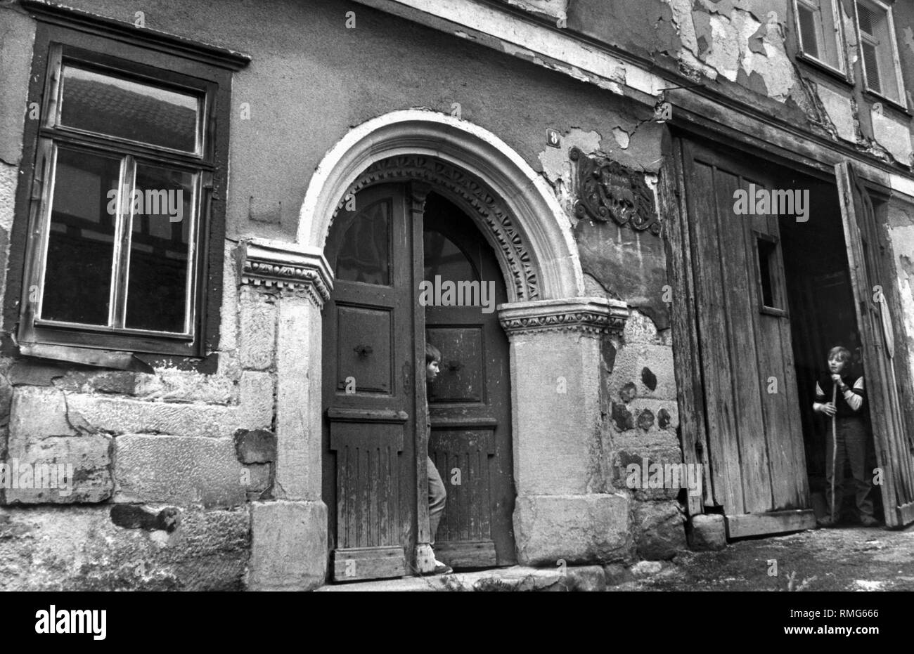 La foto mostra un ingresso di casa in Schleusingen, nell'ex RDT, da cui un ragazzo è di uscire. In corrispondenza del bordo della foto di un altro bambino è in piedi in un cortile d'ingresso appoggiato su un bastone. Foto Stock