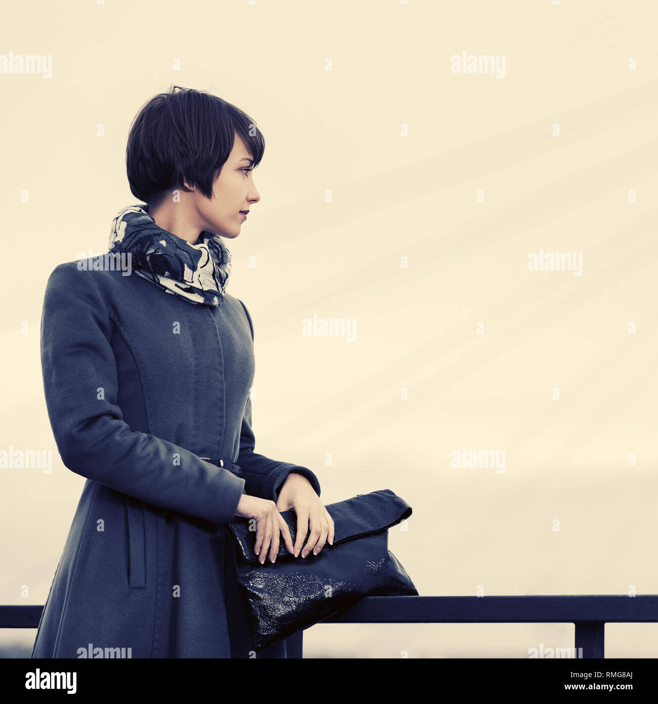 Triste moda giovane donna con borsetta outdoor elegante modello femminile in grigio cappotto classico e sciarpa Foto Stock