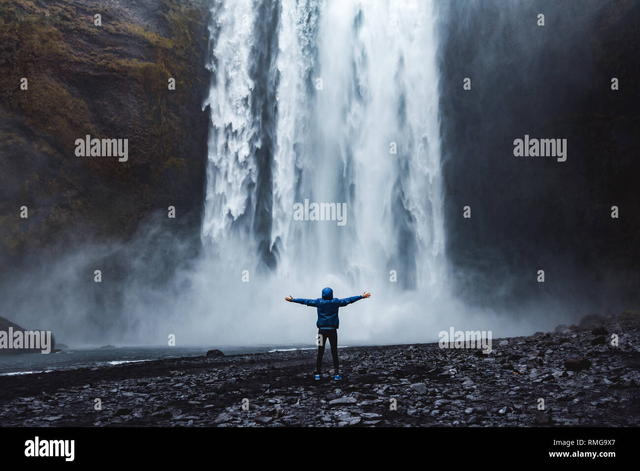 Una persona admirnig la bellezza della Cascata Skogafoss situato in Islanda Foto Stock