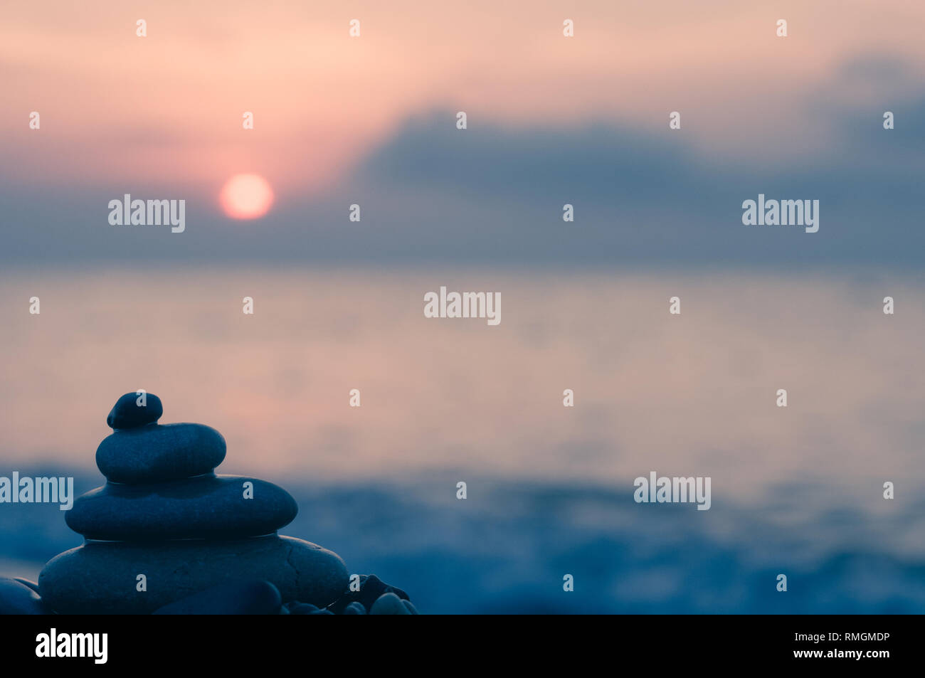 Piramide piegata Zen pietre ghiaia sul mare spiaggia al tramonto Foto Stock