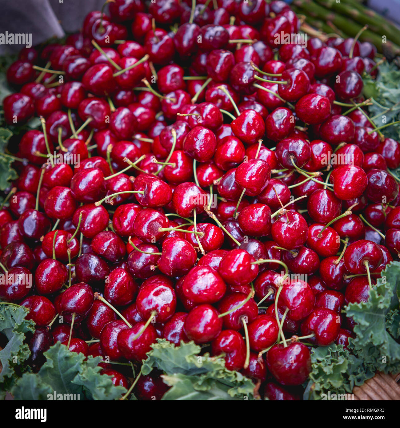 Organici di ciliege rosse in una cestella di legno in vendita in una fase di stallo in un allevatore locale mercato. Cucina di stagione. Formato quadrato. Foto Stock