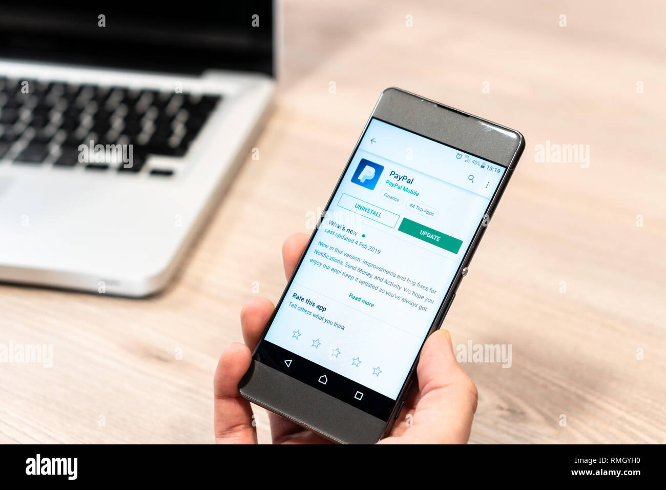 Mano umana tenendo il telefono cellulare - paypal app su app store, computer laptop in background. La Slovenia 13.02.2019 Foto Stock