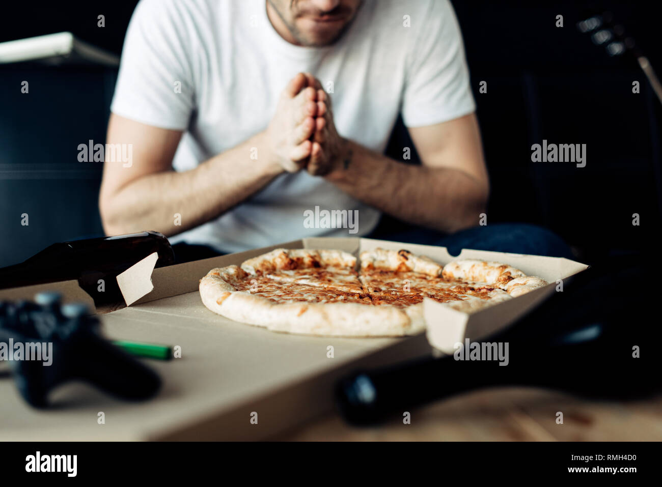 Vista ritagliata dell'uomo guardando una gustosa pizza a casa Foto Stock