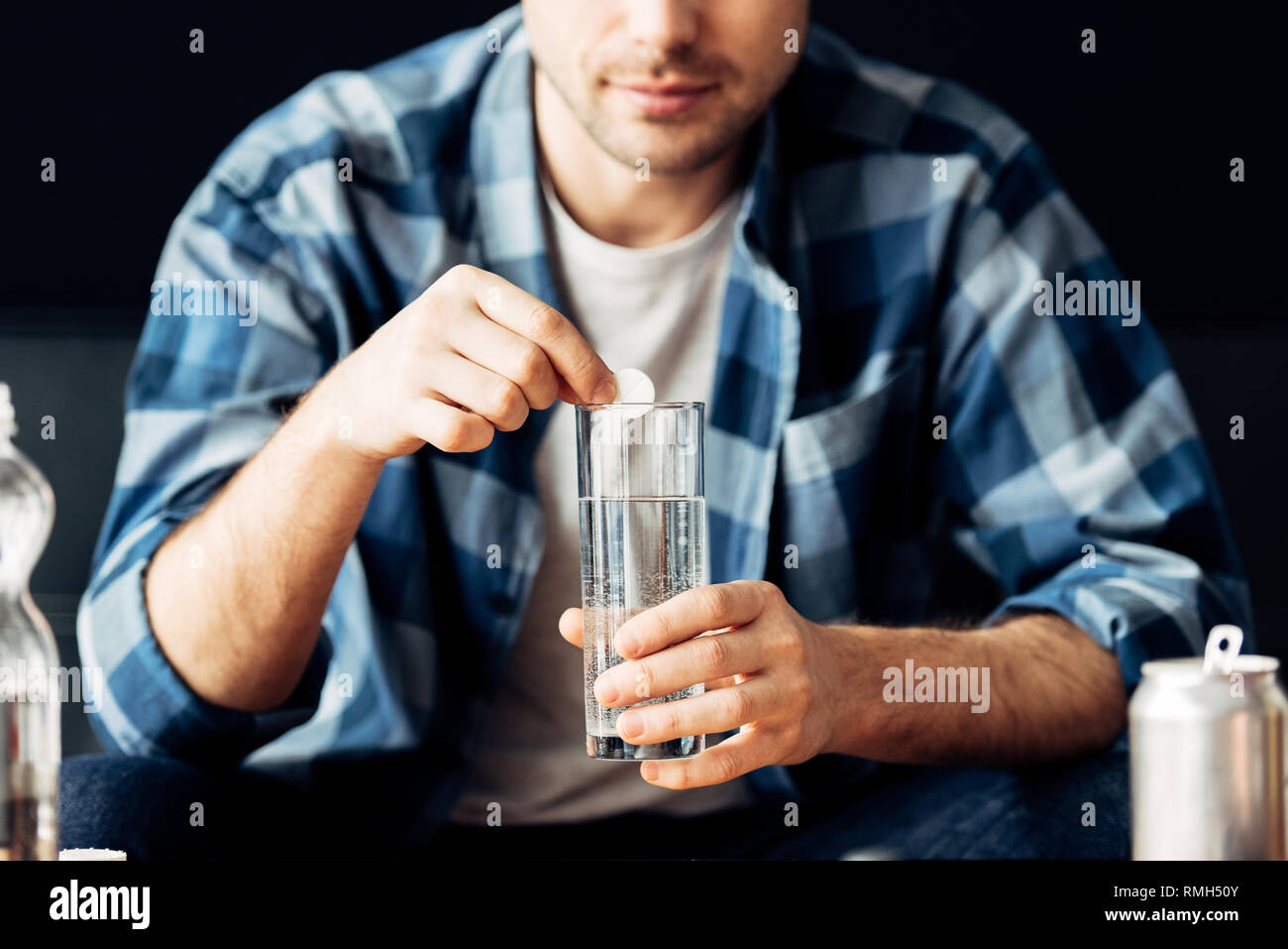 Vista ritagliata dell uomo che soffre di sbornia tenendo l'aspirina e un bicchiere di acqua in mani Foto Stock