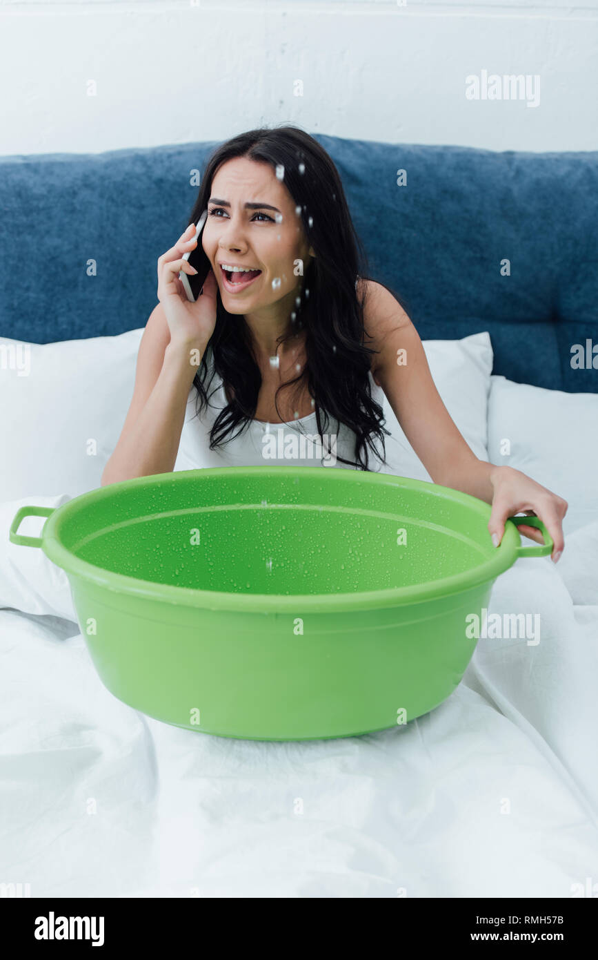 Preoccupato ragazza parlando su smartphone e bacino di contenimento a letto Foto Stock