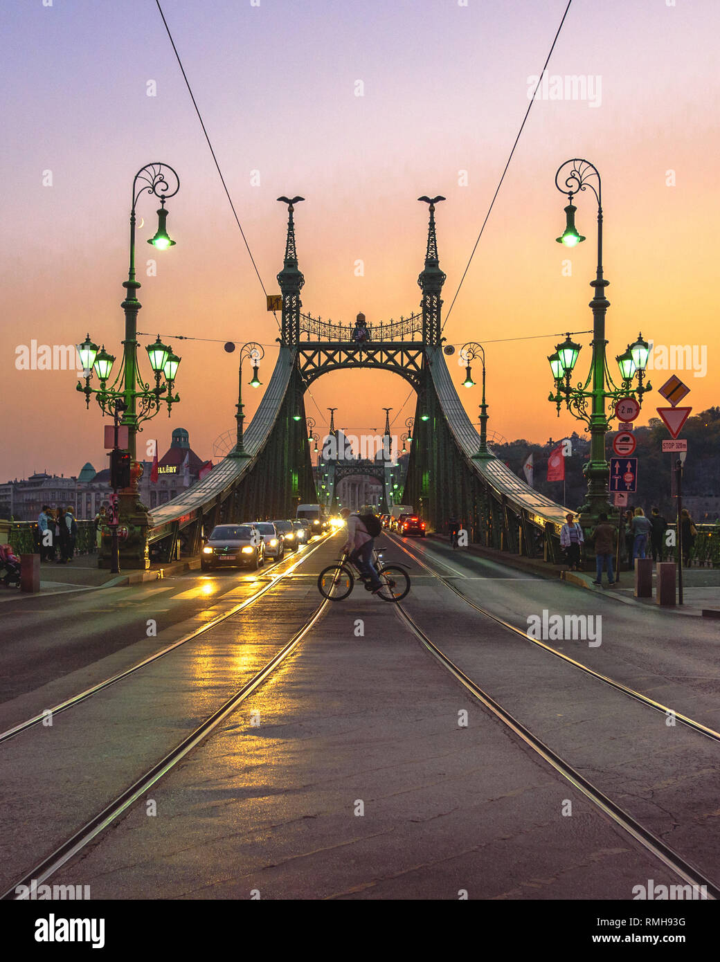 Un ciclista incrocio nella parte anteriore del ponte della Libertà a Budapest al crepuscolo Foto Stock