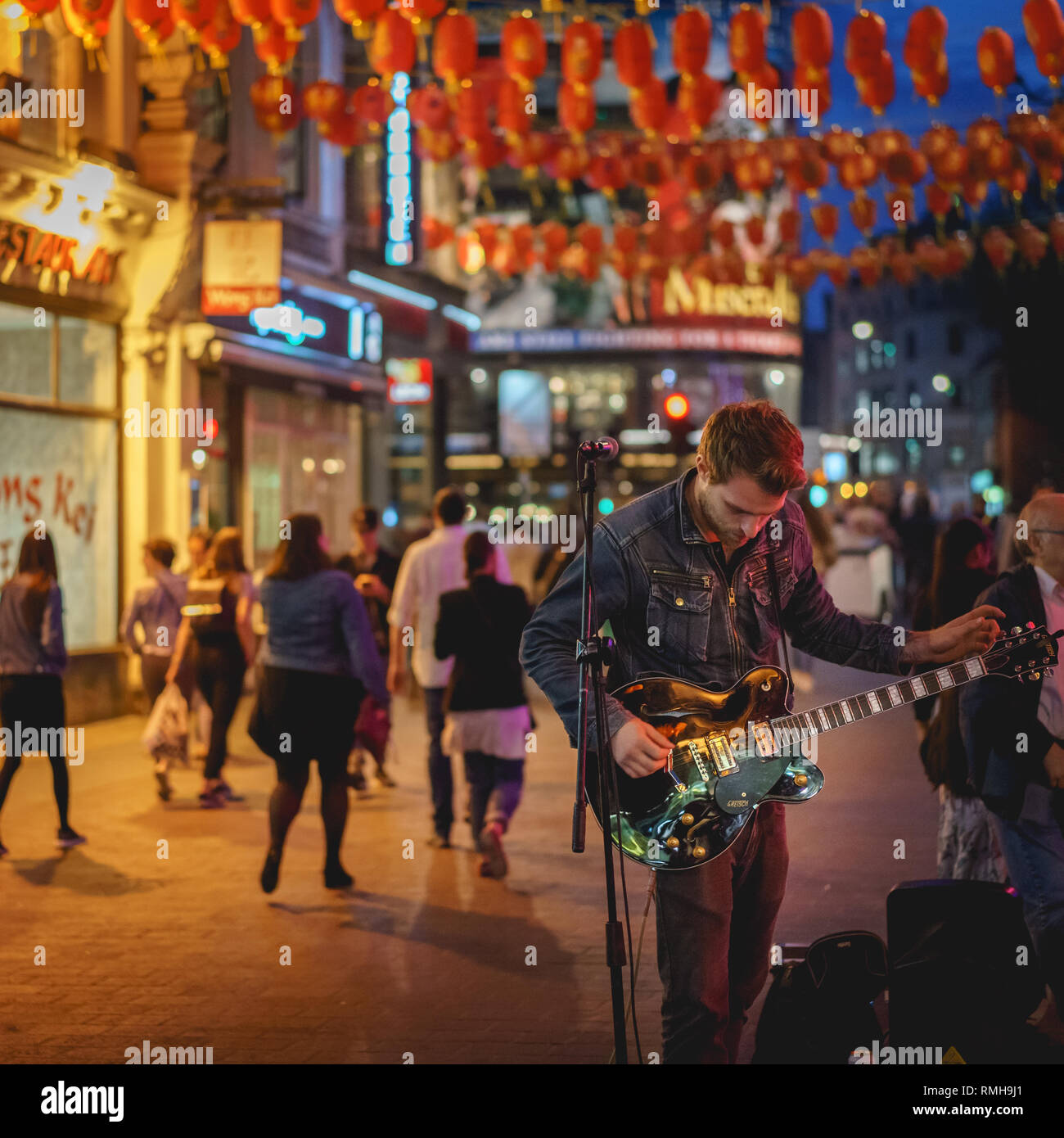 London, Regno Unito - Aprile, 2018. Musicista di strada di suonare una chitarra durante una performance in Chinatown di notte. Foto Stock