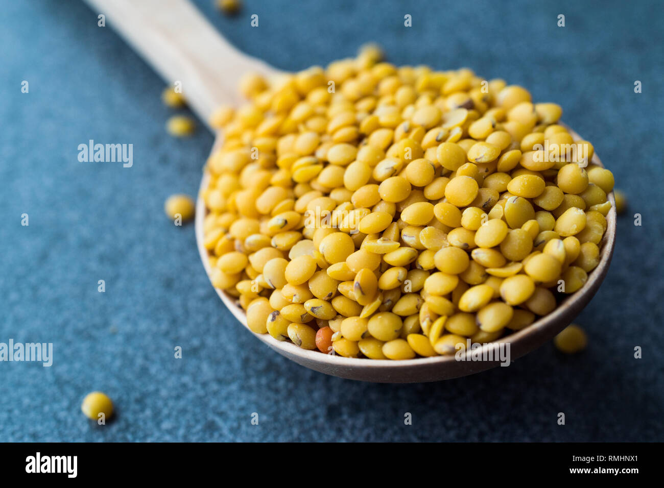Lenticchie gialle in cucchiaio di legno. Greggio prodotto organico. Foto Stock