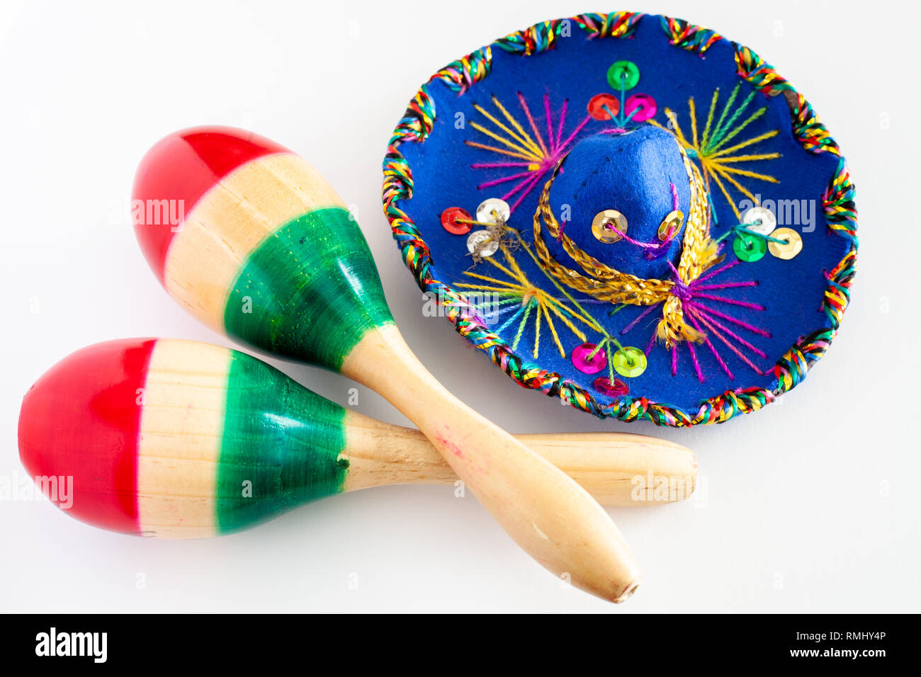 Sombrero blu con ornamenti colorati su sfondo bianco accanto alla coppia di maracas dipinte con i colori della bandiera messicana/Cinco de Mayo concept Foto Stock