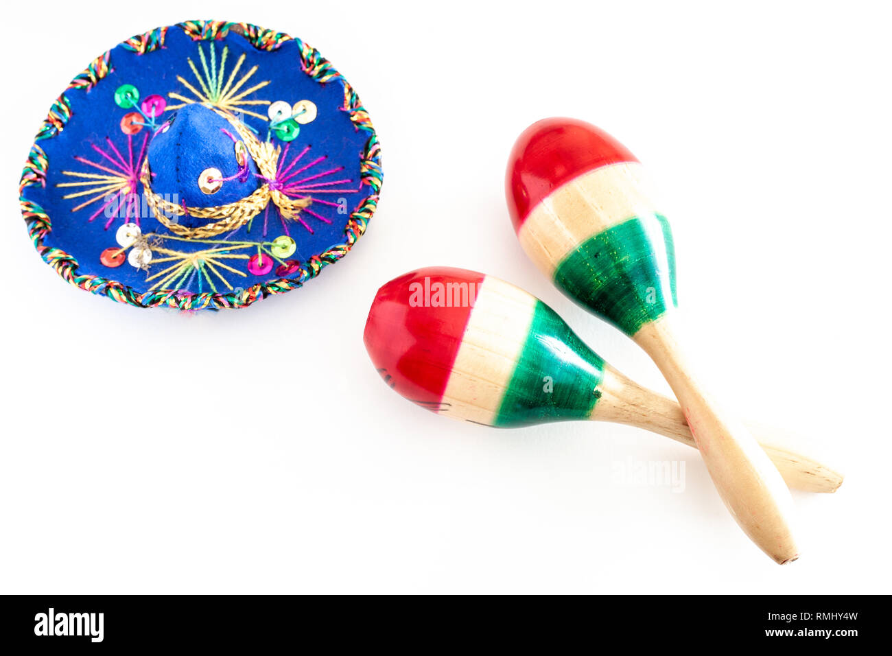 Sombrero blu con ornamenti colorati su sfondo bianco accanto alla coppia di maracas dipinte con i colori della bandiera messicana/Cinco de Mayo concept Foto Stock