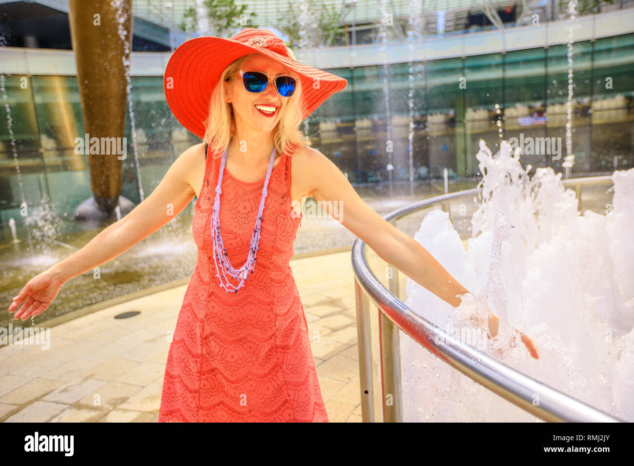 Fontana della Ricchezza a Suntec Tower, la più grande fontana in Singapore. Lo stile di vita della donna a piedi e toccare l'acqua della fontana per avere fortuna. Blonde caucasian Foto Stock