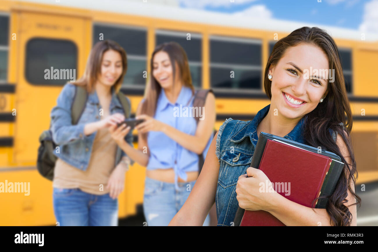 Giovane Studentessa con libri vicino a scuola bus Foto Stock