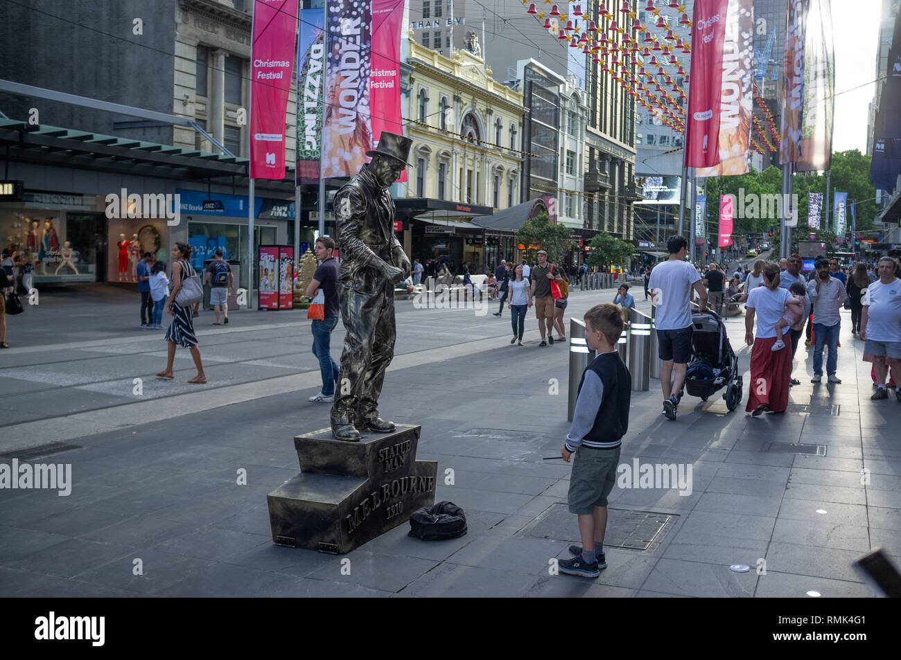 Melbourne, Australia - 1 Dicembre 2018: Boy guardando statua vivente, performer uomo di bronzo al tempo di Natale Foto Stock