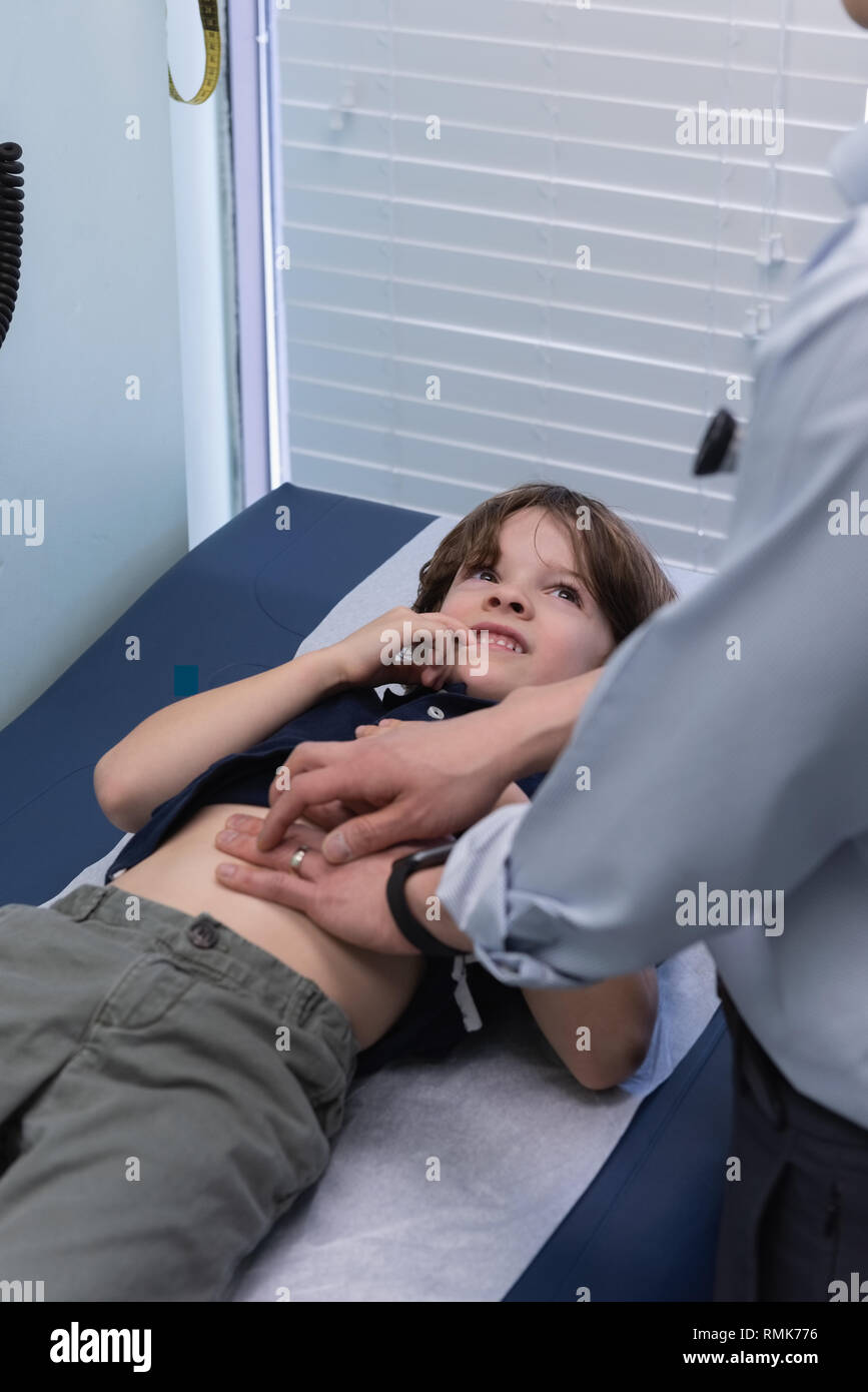 Giovani asiatici medico maschio esaminando ragazzo caucasico paziente con uno stetoscopio in clinica Foto Stock