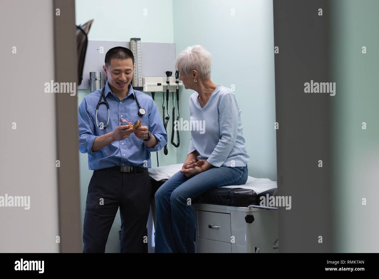 Giovane maschio asiatici medico e paziente senior discutendo su modello orecchio Foto Stock