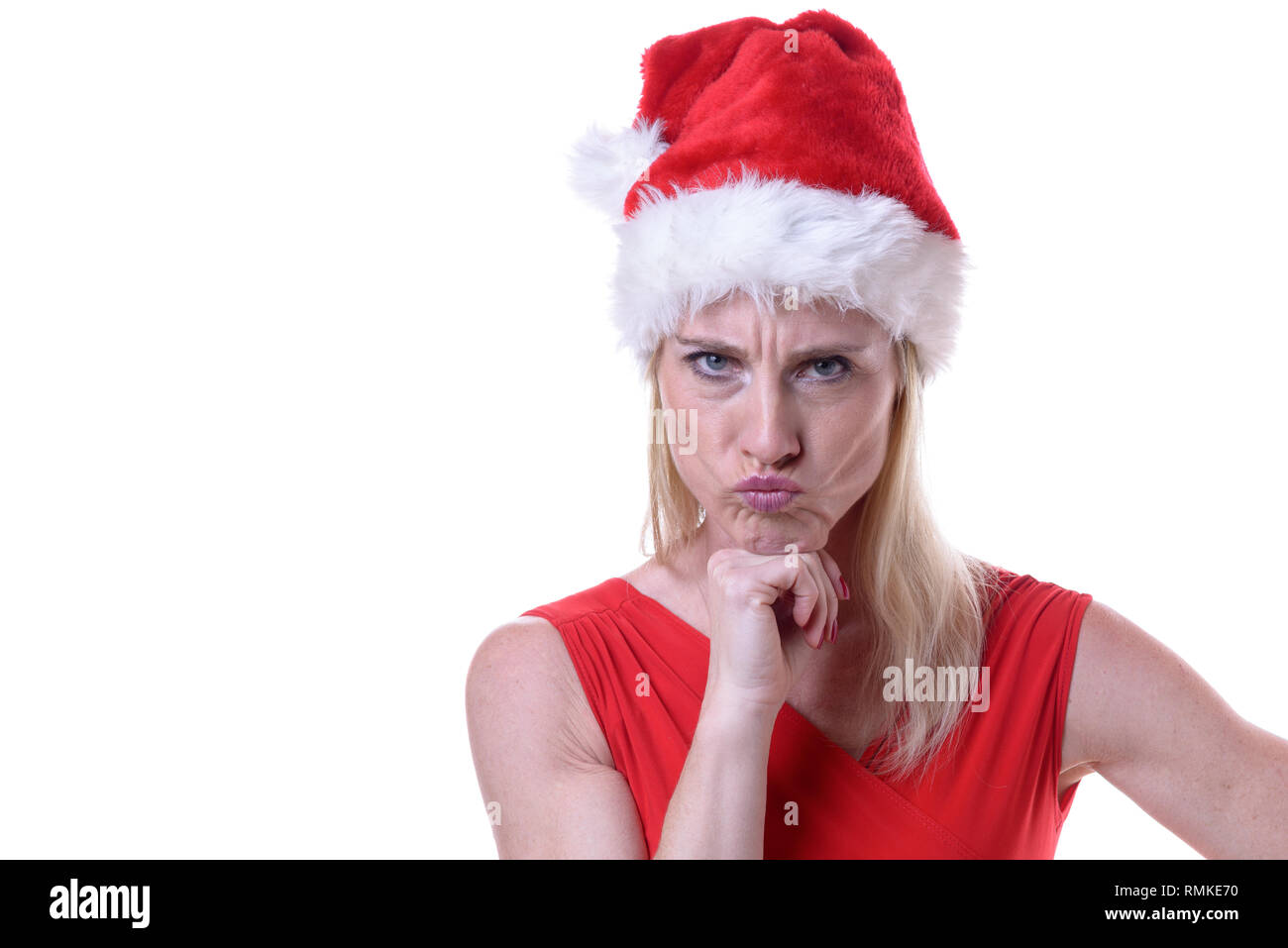 Ribelle arrabbiati donna in una festa di Santa Red Hat per celebrare il Natale a clamorose la fotocamera con un cipiglio e il suo mento sulla sua mano isolato Foto Stock