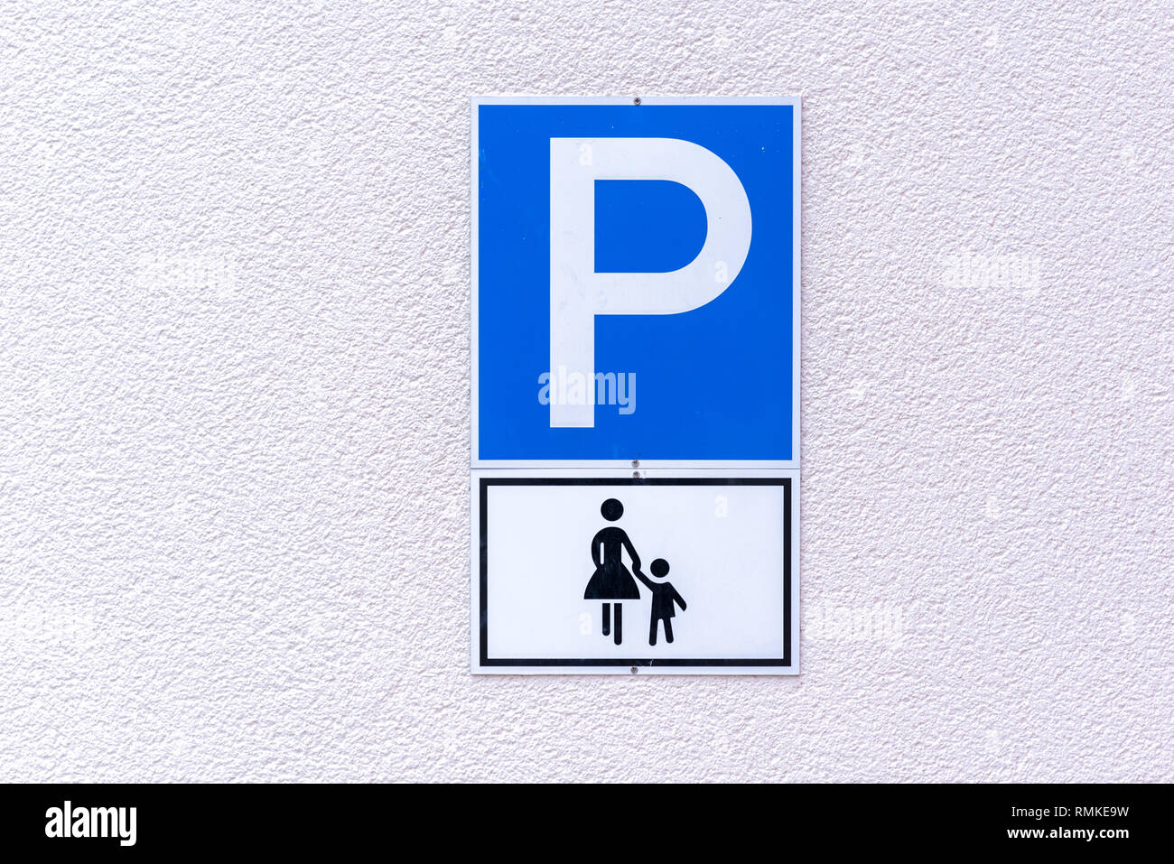 Simbolo di parcheggio per le madri con figli piccoli su un bianco goffrato parete esterna Foto Stock
