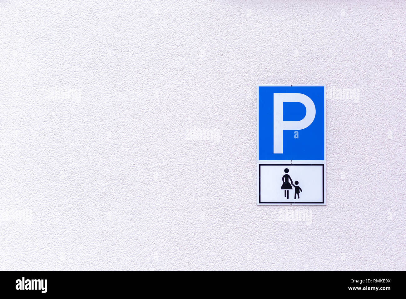 Simbolo di parcheggio per le madri con figli piccoli su un bianco goffrato esterno con la parete laterale dello spazio di copia Foto Stock