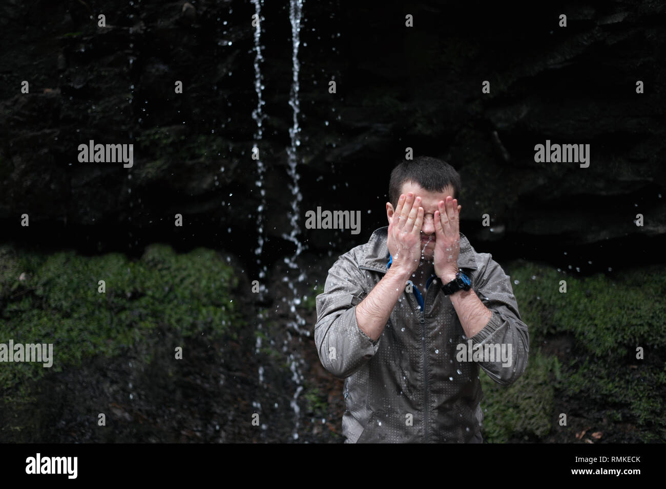 Giovane uomo russo escursionismo in Sochi Parco Nazionale: rinfrescante sotto la cascata Foto Stock