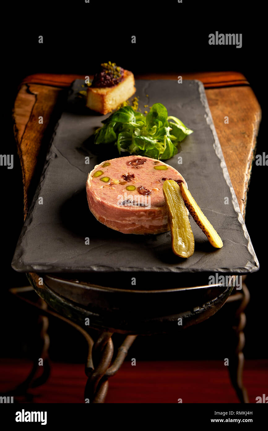 Delizioso paté d'anatra servito con una fetta di pane tostato e un sottaceti a fette Foto Stock