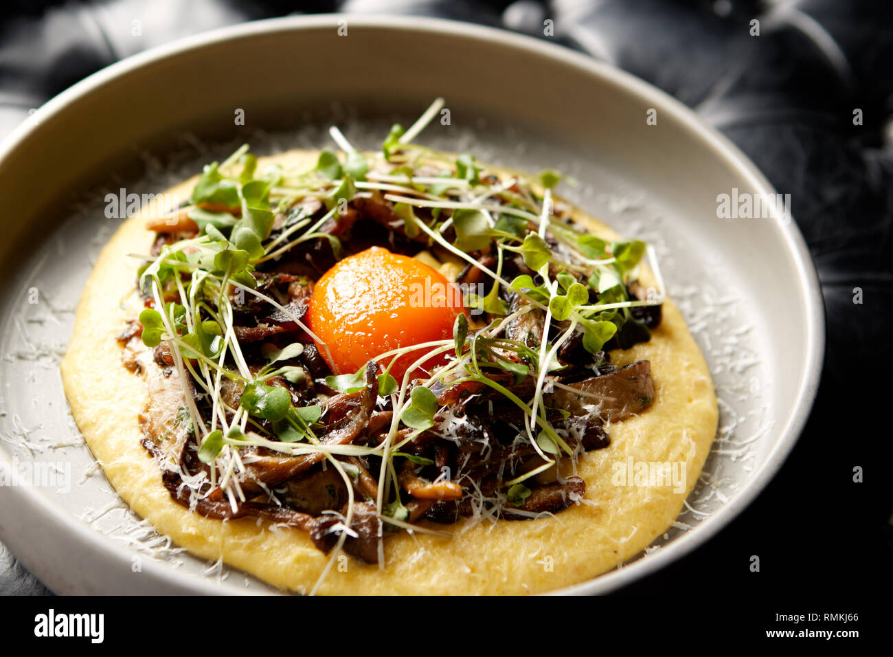 Primo piano di un antipasto cremoso e delizioso composto da funghi, germogli, purea di patate e tuorlo d'uovo. Foto Stock