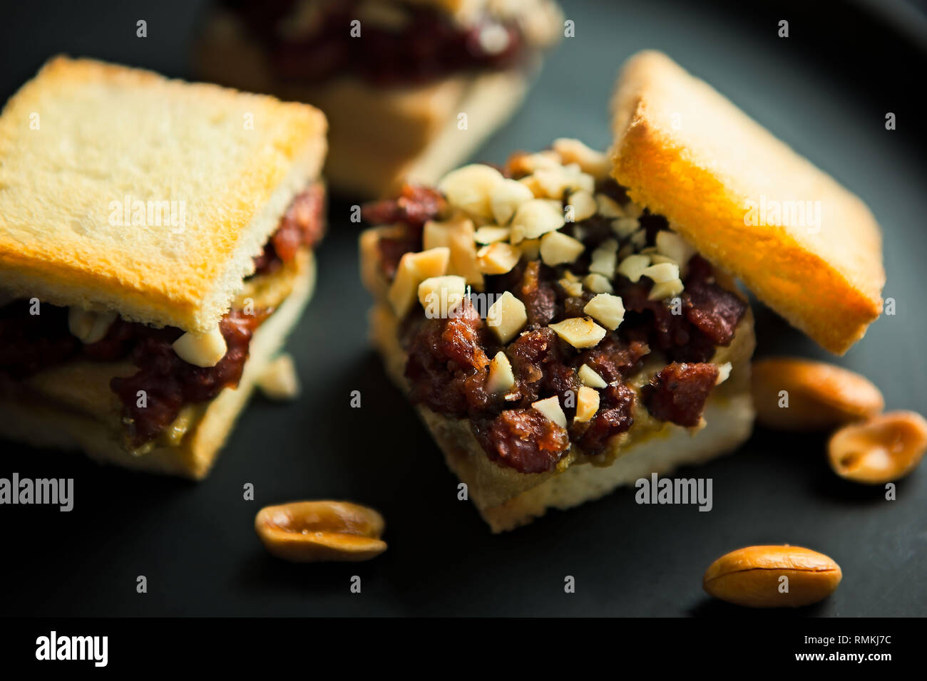 Viene servito un primo piano con noci croccanti e mini sandwich tostati con datteri su una piastra grigia Foto Stock