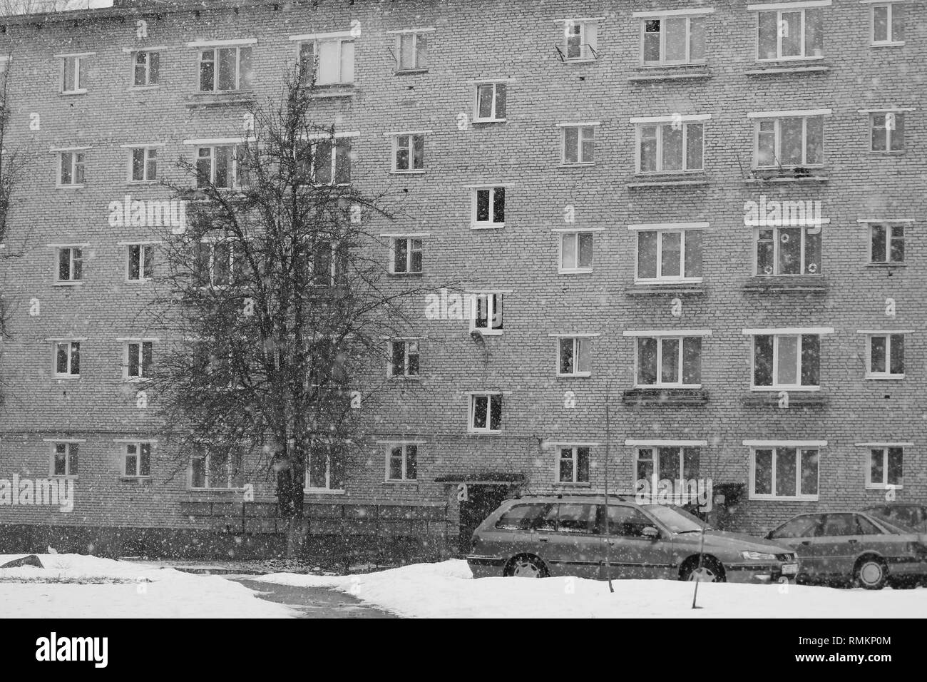 Inverno per le strade delle città con mura grigie della costruzione nel freddo giorno di neve Foto Stock