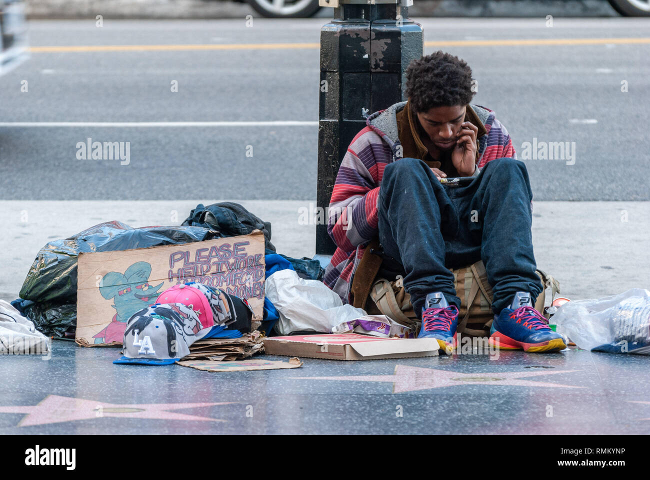 Los Angeles, California, Stati Uniti d'America - 8 gennaio 2017. Senzatetto su Sunset Boulevard a Los Angeles, seduto per terra con il suo b Foto Stock
