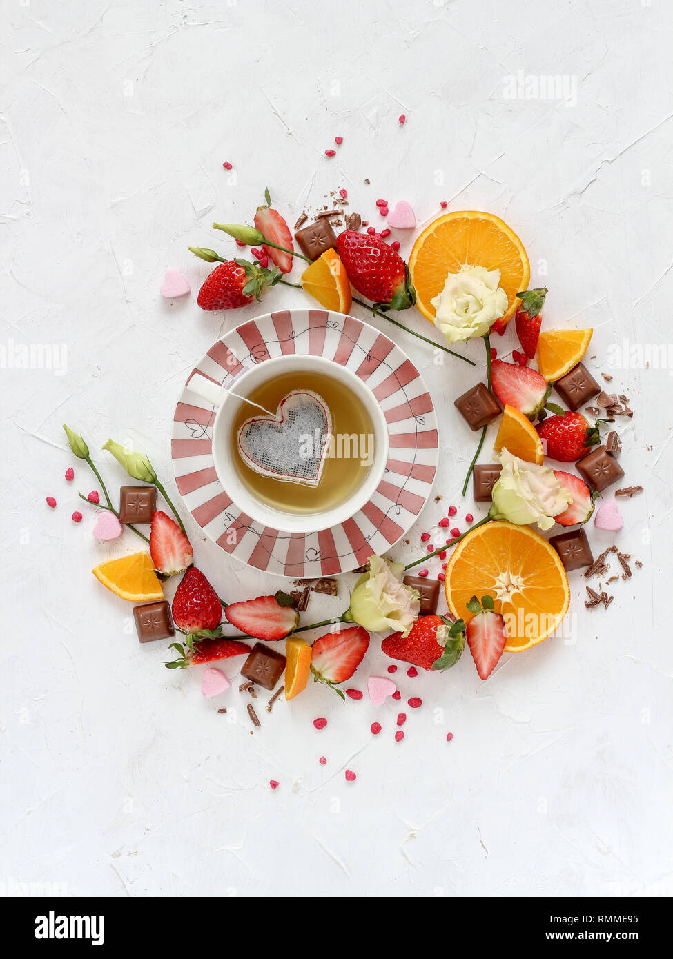 Composizione del cerchio di frutta mista e una tazza di tè a forma di cuore sacchetto da tè in medio su uno sfondo luminoso Foto Stock