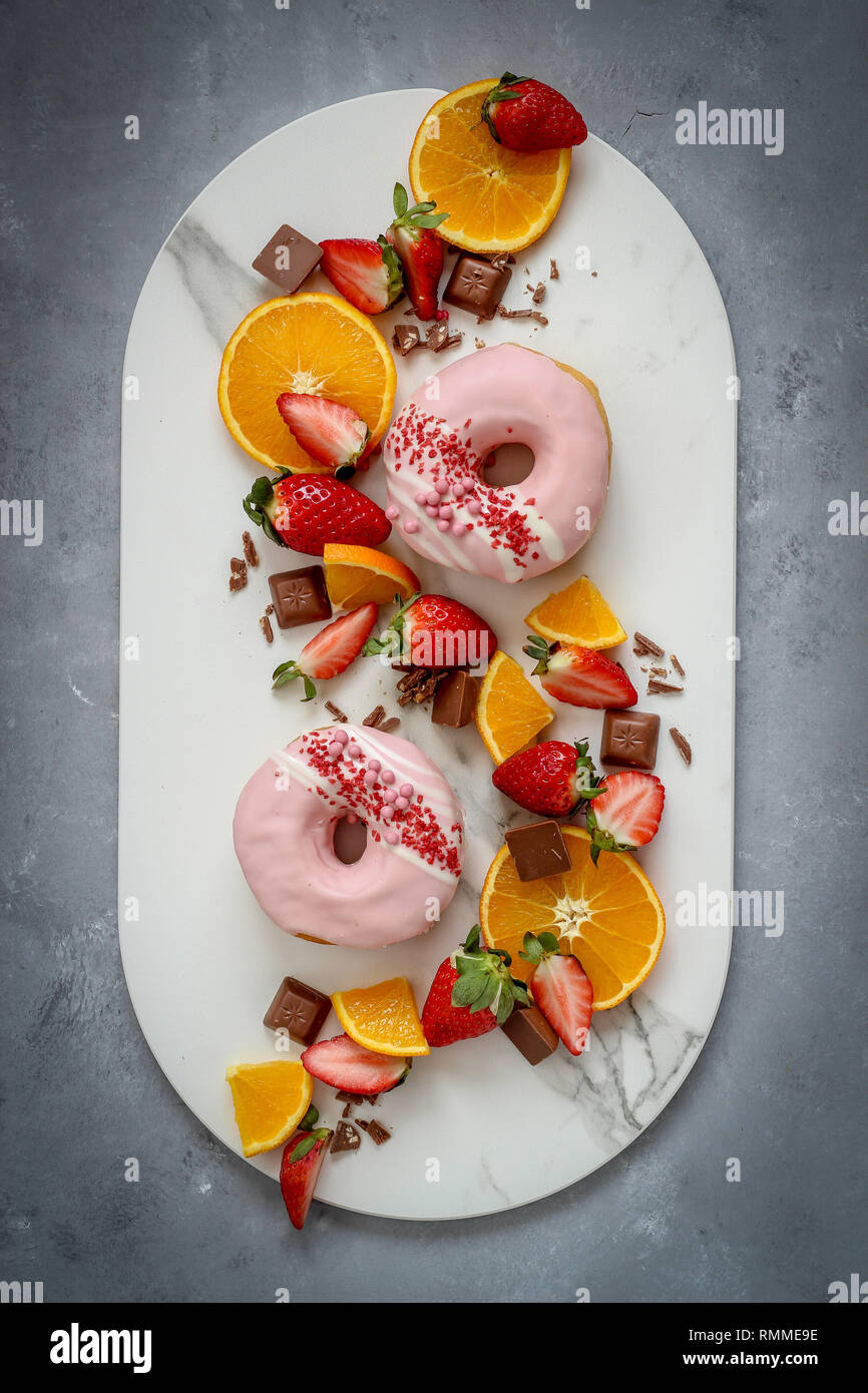 Un misto di frutta con ciambelle su sfondo scuro Foto Stock