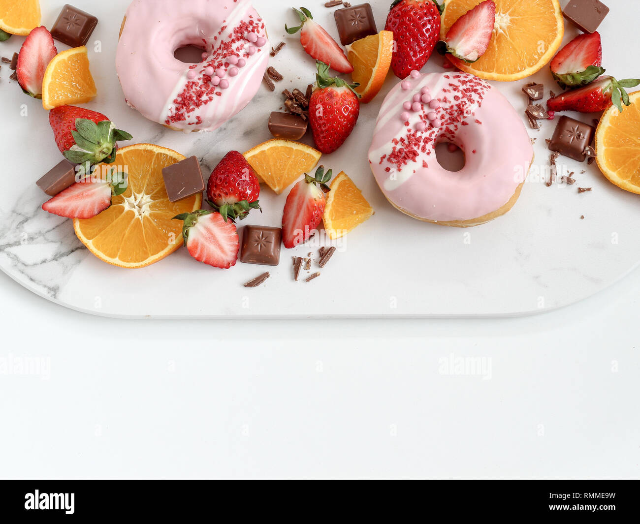 Un mix di fragole, arancio, cioccolato e ciambelle su uno sfondo luminoso Foto Stock