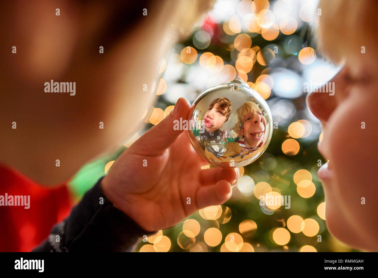 La riflessione di due ragazzi rendere divertente volti in una pallina di Natale Foto Stock
