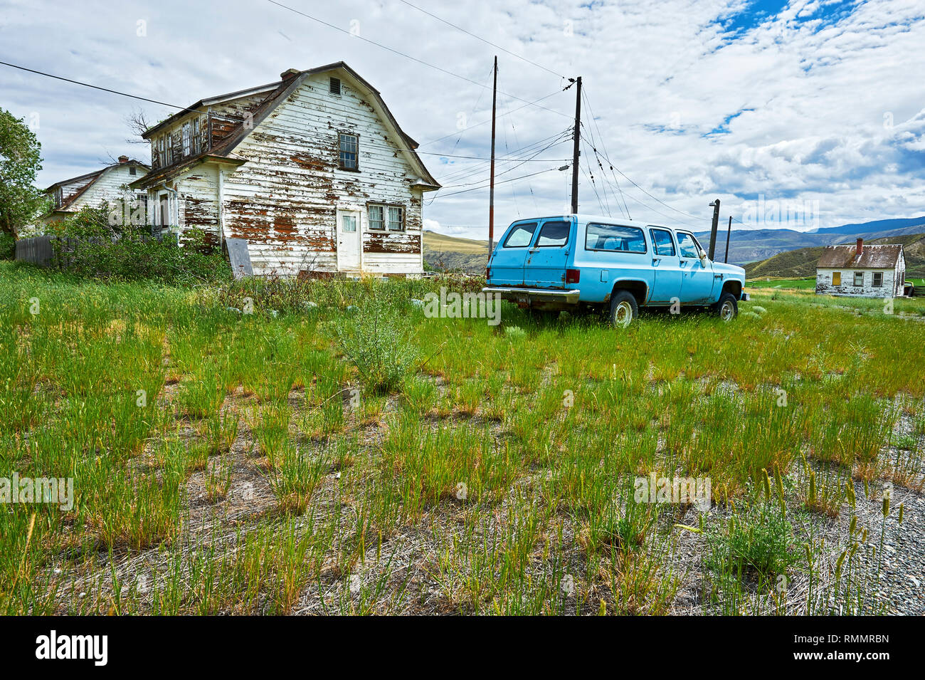Lillooet, B.C., Canada - 30 Giugno 2012: Insediamento di poche case su ampi terreni di erba lungo l'autostrada 99, fotografati da un basso angolo di visione Foto Stock