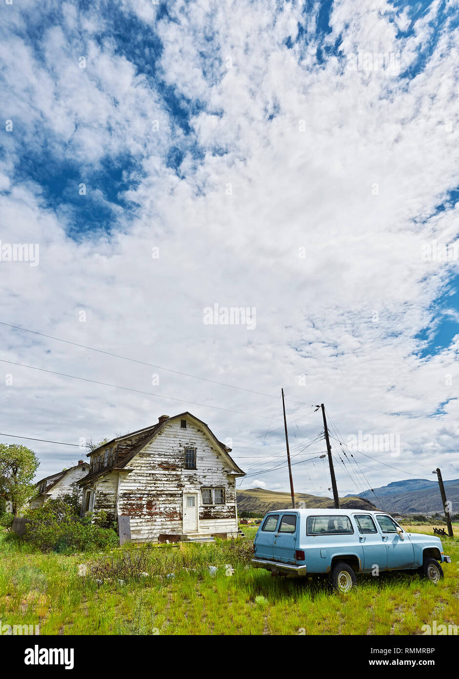 Lillooet, B.C., Canada - 30 Giugno 2012: Insediamento di poche case su ampi terreni di erba lungo l'autostrada 99, fotografati da un basso angolo di visione Foto Stock