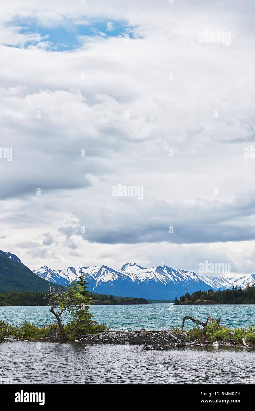 Vista panoramica del lago Chilko con montagne coperte di neve e un cielo nuvoloso come sfondo, British Columbia, Canada Foto Stock