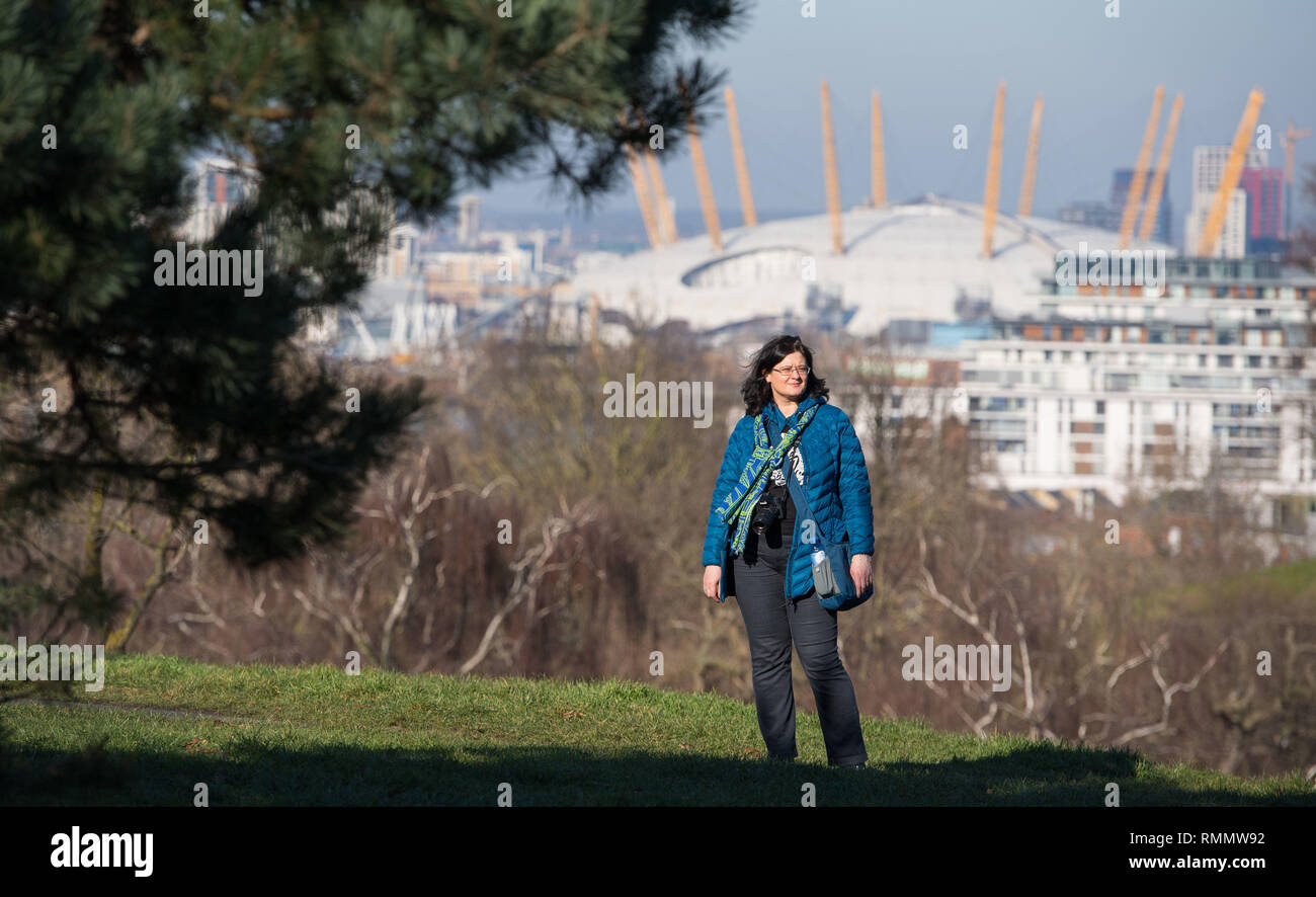 Una donna cammina al sole nel parco di Greenwich, Londra del sud. Forecasters hanno previsto un altro giorno di tempo caldo il venerdì dopo unseasonably clima mite ha visto il più caldo il giorno di San Valentino in più di venti anni il giovedì con un massimo di 16.1C (61F) registrate nella cittadina gallese di Bala, Gwynedd. Foto Stock